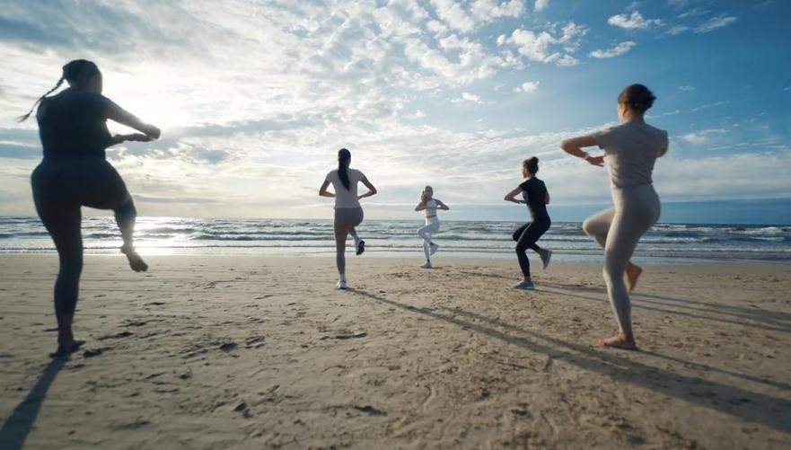 Smartwatch untuk Berlari - Panduan Terbaik Peningkat Performa Anda! 2 Seorang pelari wanita sedang menggunakan smartwatch untuk berlari di jalur lari outdoor